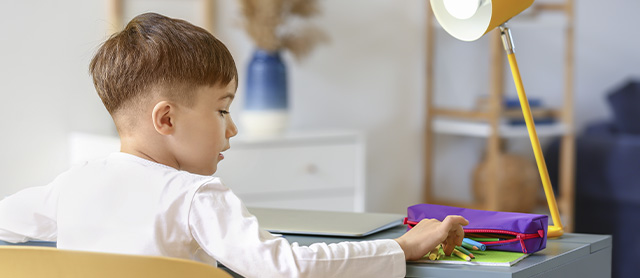 menininho desenhando e pegando materiais em seu estojo