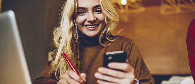 mulher conferindo o celular para organizar sua rotina em um planner