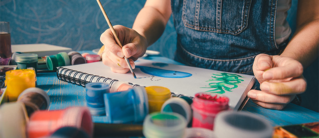 mulher pintando com vários potes de tinta ao seu redor