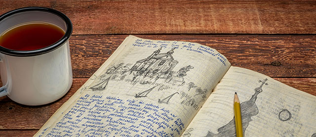 diário de viagem com desenhos ao lado de uma xícara de café