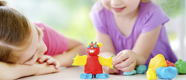 duas meninas na creche contando histórias com massinha de modelar